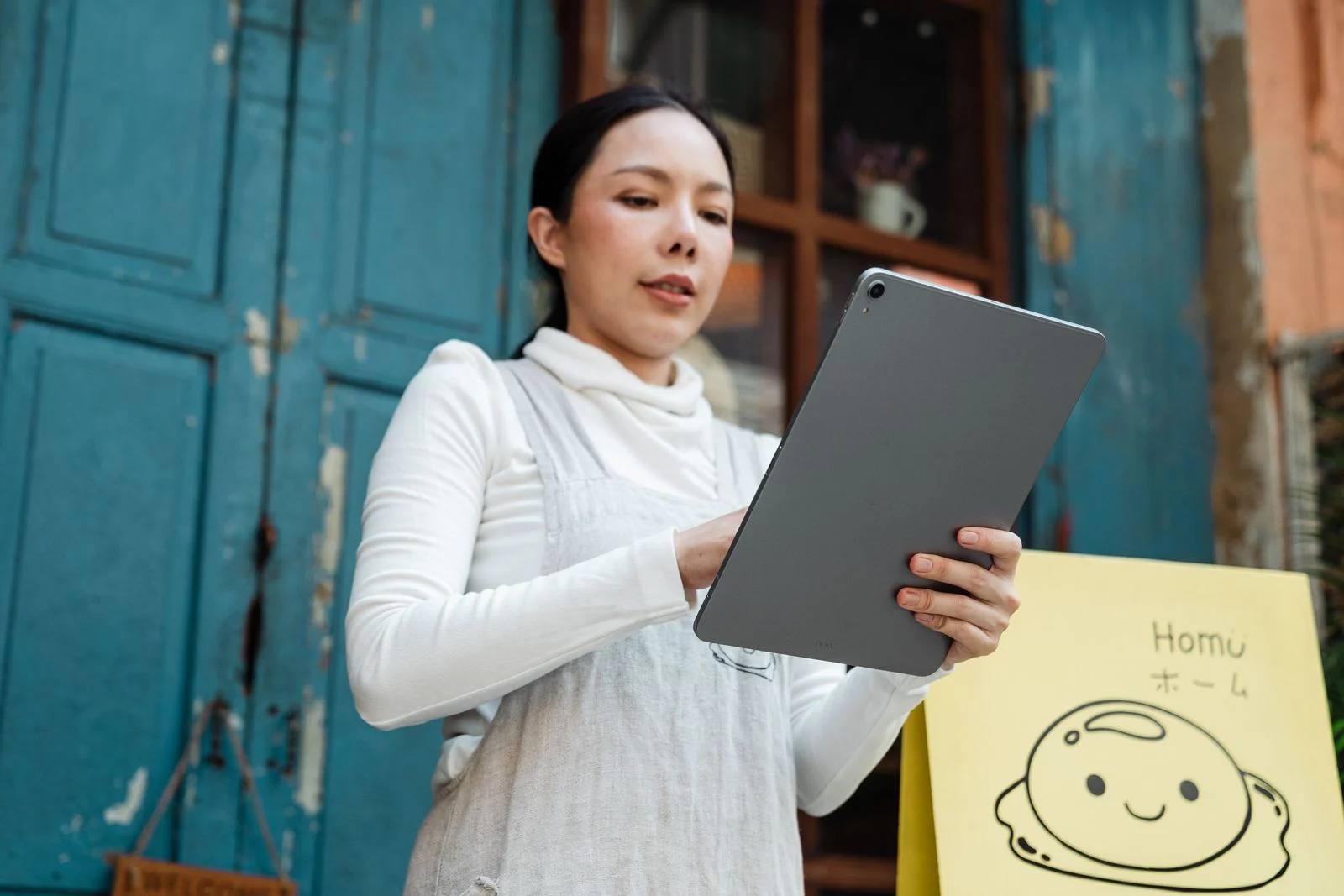 A shop owner checking her tablet outside her shop