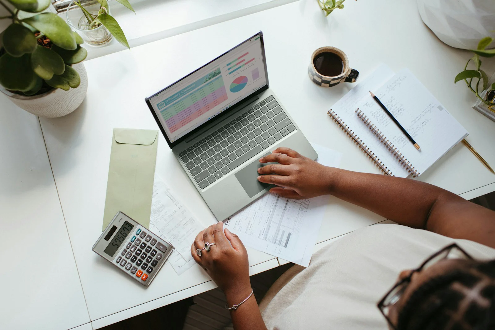 Founder planning at a desk with charts on a laptop, a calculator and notes